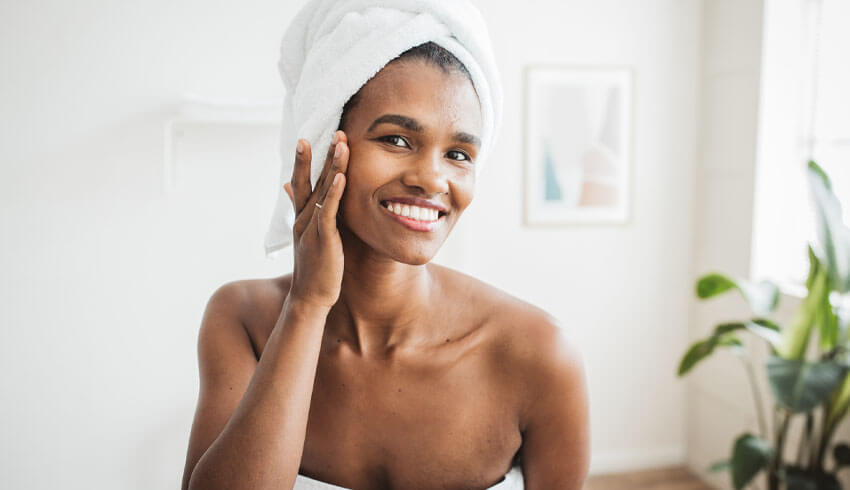 A woman in towel touching face in mirror